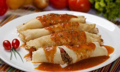 Quatro panquecas de carne moída com molho de tomate, guarnecidas com tomates cereja em prato branco