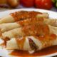 Quatro panquecas de carne moída com molho de tomate, guarnecidas com tomates cereja em prato branco