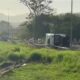 Caminhão branco tombado em acostamento de rodovia, com detritos e grama ao redor