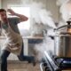 Homem assustado com panela de pressão jorrando vapor e espuma no fogão da cozinha. (Imagem ilustrativa de IA)