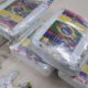 Blocos de maconha prensada com adesivos de bandeiras e 'MILIONARIO 9', e um saco pequeno de erva