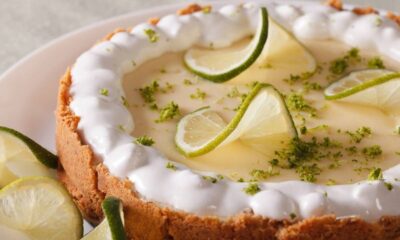 Fatia de torta de limão fresca com cobertura branca, raspas e fatias de limão em prato