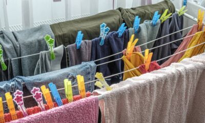 Varal de chão com roupas coloridas e toalhas penduradas e presas por prendedores em ambiente interno