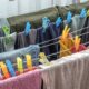 Varal de chão com roupas coloridas e toalhas penduradas e presas por prendedores em ambiente interno