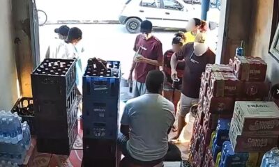 Interior de bar ou comércio de bebidas com pessoas, garrafas e caixas empilhadas