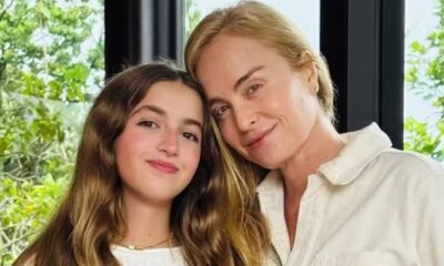 Angélica e sua filha Eva, sorrindo e com cabeças juntas, em frente a uma folhagem verde