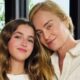 Angélica e sua filha Eva, sorrindo e com cabeças juntas, em frente a uma folhagem verde