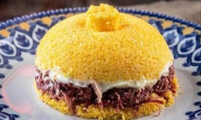 Cuscuz nordestino recheado com carne seca desfiada em um prato azul e branco