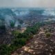 Paisagem amazônica com extensas áreas queimadas escuras, vegetação verde e fumaça