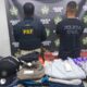 Dois policiais de costas, um da PRF, exibem roupas de marca apreendidas sobre mesa