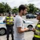 Dois agentes de trânsito (Detran-RJ) e um civil conversam em fiscalização, carro e moto policiais