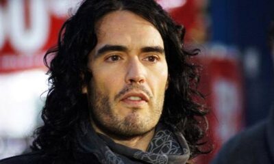 Retrato de Russell Brand com cabelo comprido e escuro, barba e expressão séria