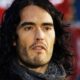 Retrato de Russell Brand com cabelo comprido e escuro, barba e expressão séria