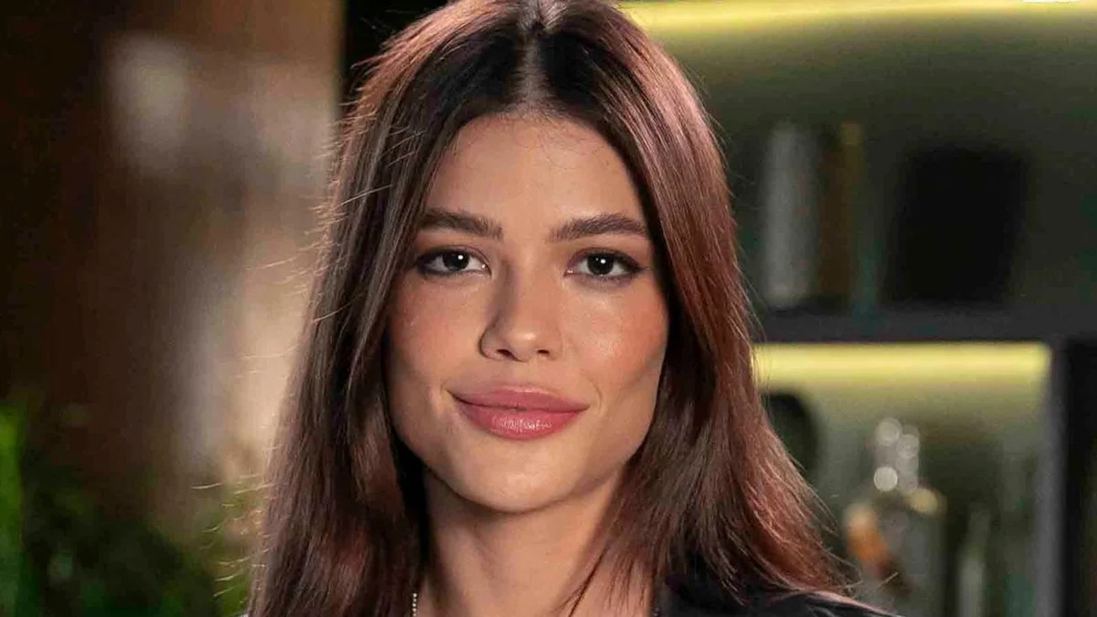 Retrato frontal de uma mulher jovem com cabelos castanhos escuros e sorriso sutil