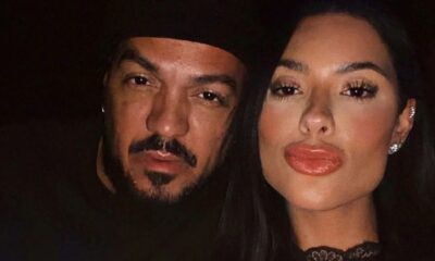 Close-up de Belo, com barba e boné, e Rayane Figliuzzi, com lábios marcantes