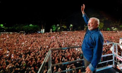 Presidente Lula no palco, acenando para uma vasta multidão com celulares acesos, à noite