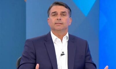 Homem de terno azul, camisa branca, em estúdio de TV azul, olhando à frente