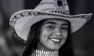 Mulher jovem sorrindo, usando chapéu de cowboy decorado e gargantilha, em preto e branco