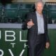 Clint Eastwood, terno xadrez, camisa cinza, apontando. Fundo: letras "DUBL HTH IDV", assentos