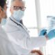 Médico de máscara e luvas aponta radiografia de tórax para paciente