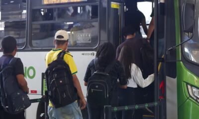Pessoas com mochilas embarcam em um ônibus público verde e branco