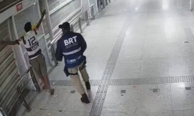 Agente do BRT Seguro com colete detém homem de camisa 12 e braços erguidos em estação