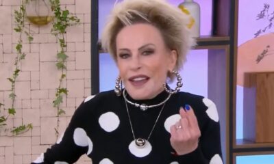 Ana Maria Braga, cabelo loiro curto, blusa preta de bolinhas brancas, gesticula em estúdio