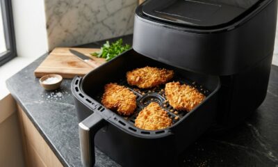 Air fryer com gaveta aberta mostrando filés de frango empanados dourados e crocantes, organizados com espaço entre eles para um cozimento uniforme. - Imagem ilustrativa criada por inteligência artificial