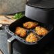 Air fryer com gaveta aberta mostrando filés de frango empanados dourados e crocantes, organizados com espaço entre eles para um cozimento uniforme. - Imagem ilustrativa criada por inteligência artificial