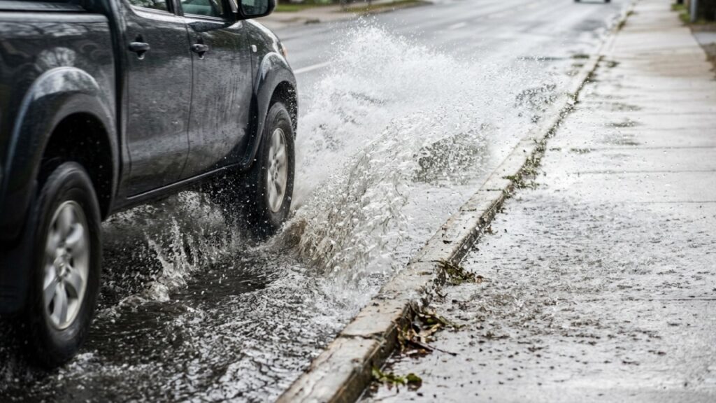 Motorista passa rápido por uma poça, molha um pedestre na calçada e descobre que a “brincadeira” pode virar infração, com multa e 4 pontos na CNH