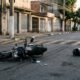 Motocicleta preta caída no asfalto próximo a uma lombada em avenida urbana, representando acidente durante corrida de moto por aplicativo. - Imagem ilustrativa criada por inteligência artificial