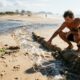 Pai ajuda o filho a cavar um "pequeno rio" entre uma lagoa e o mar durante brincadeira na praia, mas a força da água começa a alargar o canal e transforma a diversão em um possível problema ambiental