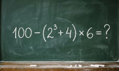 Quadro-negro escolar com a expressão 100 − (2³ + 4) × 6 = ? escrita em giz branco, apresentando um desafio de matemática sem revelar o resultado. - Imagem ilustrativa criada por inteligência artificial