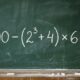 Quadro-negro escolar com a expressão 100 − (2³ + 4) × 6 = ? escrita em giz branco, apresentando um desafio de matemática sem revelar o resultado. - Imagem ilustrativa criada por inteligência artificial