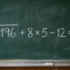 Quadro-negro escolar com a expressão √196 + 8 × 5 − 12 = ? escrita em giz branco, apresentando um desafio de cálculo mental com raiz quadrada. - Imagem ilustrativa criada por inteligência artificial