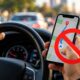 Motorista segura o celular para consultar o GPS durante uma viagem pela rodovia, é parado em uma fiscalização e descobre que o hábito pode render multa de R$ 293,47 e 7 pontos na CNH