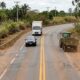 Carro preto ultrapassa trator verde em rodovia de pista simples com faixa dupla amarela contínua, enquanto caminhão se aproxima no sentido contrário. - Imagem ilustrativa criada por inteligência artificial