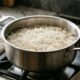 Panela de inox com arroz branco soltinho, grãos inteiros e bem separados, sobre um fogão em cozinha iluminada naturalmente. - Imagem ilustrativa criada por inteligência artificial
