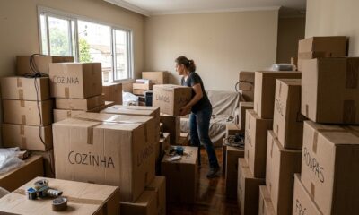 Mulher transporta caixa de 'LIVROS' em sala repleta de caixas de papelão rotuladas