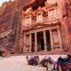 Fachada de Al-Khazneh em Petra, Jordânia, com três camelos coloridos no deserto