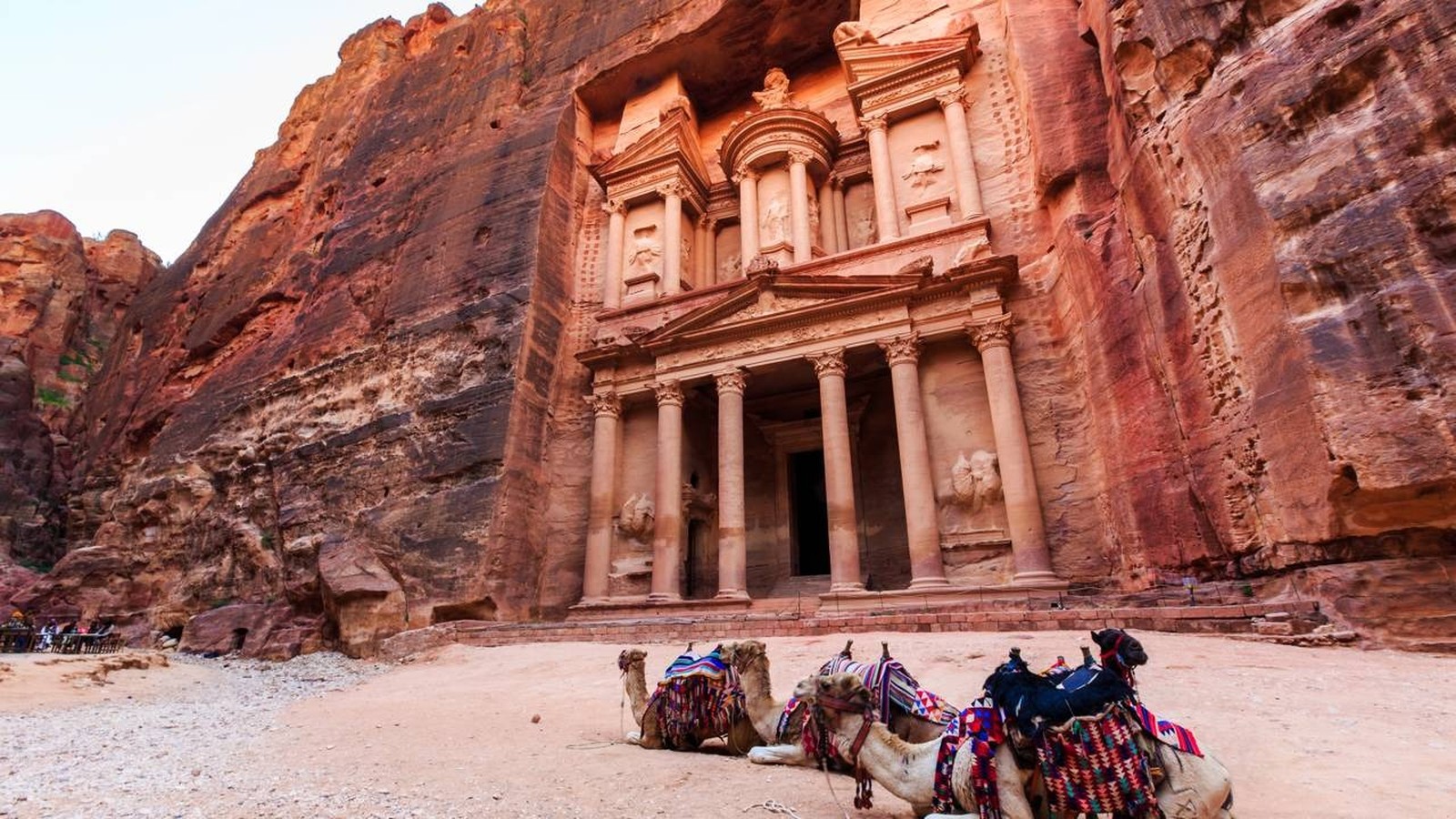 Fachada de Al-Khazneh em Petra, Jordânia, com três camelos coloridos no deserto