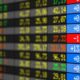 Painel digital da bolsa de valores exibindo cotações e variações em vermelho, azul, verde e amarelo
