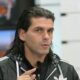 Homem de cabelo comprido e jaqueta preta Adidas gesticula enquanto fala