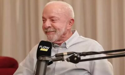 Lula sorrindo, barba branca, camisa clara, em frente a microfone Flow Podcast