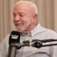 Lula sorrindo, barba branca, camisa clara, em frente a microfone Flow Podcast