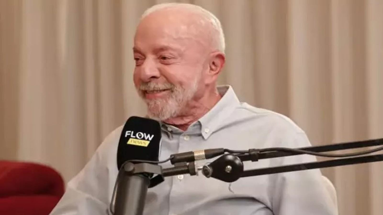 Lula sorrindo, barba branca, camisa clara, em frente a microfone Flow Podcast