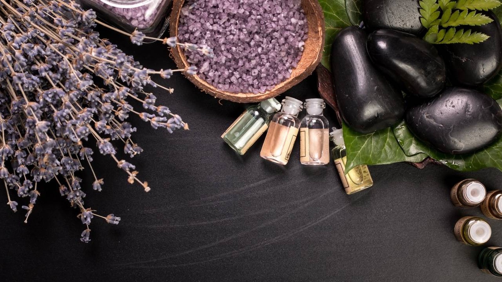 Flores de lavanda, sais de banho, óleos essenciais, pedras e folhas em ambiente spa