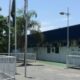 Fachada de clínica com letreiro "CLÍNICA DA FAMÍLIA", cercas brancas e postes com bandeiras