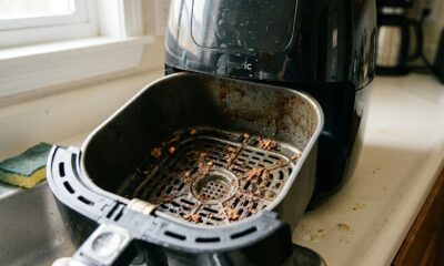 Cesta suja de air fryer com restos de comida e gordura, sendo removida da base