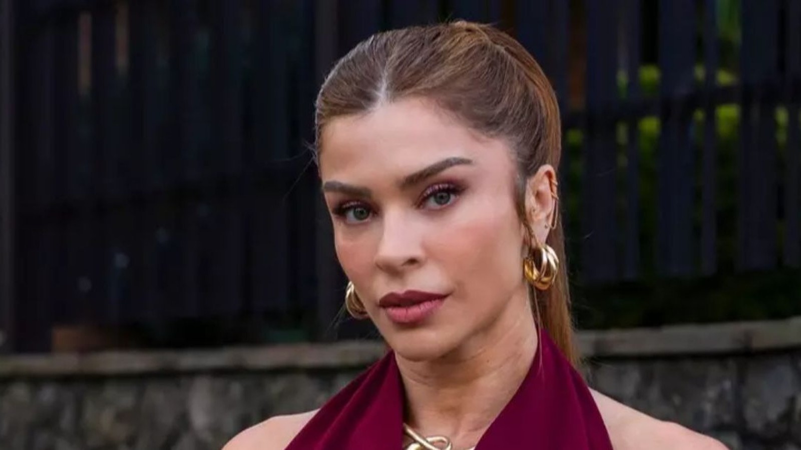 Close-up da atriz Grazi Massafera com cabelo castanho, blusa vinho e brincos dourados